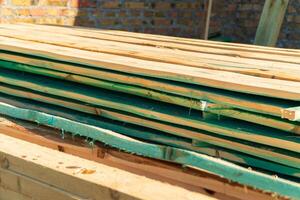 The board is stacked on the construction site. The board is used in the construction of houses. Material for construction photo