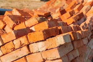 The red bricks is stacked on the construction site. The red bricks is used in the construction of houses. Material for construction photo