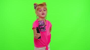 Cheerful funny little teen girl kid dancing at camera filming using phone at home on chroma key background. Schoolgirl child creating her trendy content on a mobile app to share on social media video