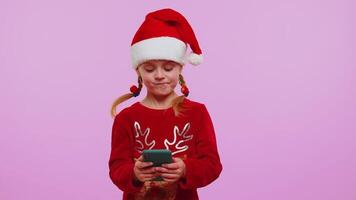 Girl in Christmas deer sweater using mobile phone typing new post on web, sms message, browsing, addiction of social networks. Violet background. Happy New Year celebration holidays shopping online video