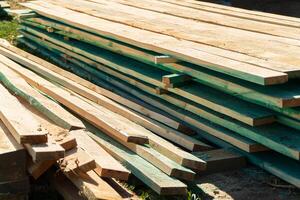 Building boards lying in a pile at a construction site. Boards for roof construction. Boards building material. Construction of a house photo