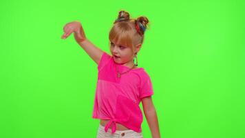 Joyful little Caucasian kid girl blogger front of phone camera record enjoy dance content on green chroma key background. Social distance coronavirus pandemic concept. Freedom active lifestyle video
