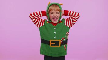Dont want to hear and listen. Frustrated irritated kid in Christmas Santa helper Elf costume covering ears, gesturing no, avoiding advice ignoring unpleasant noise loud voices. Happy New Year holiday video