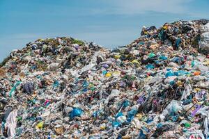 Pile of domestic garbage in landfill dump site. A pile of garbage in a landfill against a blue sky photo