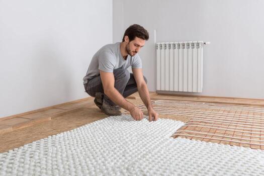 Man installing a heating pad on a floor photo