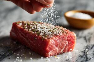 A person sprinkling salt on a piece of meat photo
