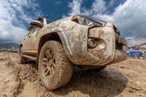 A muddy suv driving on a dirt road photo