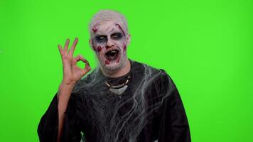 Creepy man with bloody scars face, Halloween stylish zombie make-up. Scary wounded undead guy looking approvingly at camera showing Ok gesture, like sign positive something good and smiles terribly video