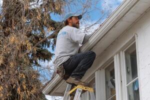 A man on a ladder working on the roof of a house photo