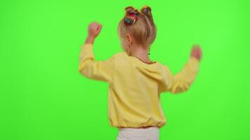 Cheerful funny little teen girl kid dancing at camera filming using phone at home on chroma key background. Schoolgirl child creating her trendy content on a mobile app to share on social media video