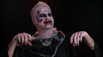 Sinister man horrible scary Halloween zombie listening music dancing disco fooling around having fun expressive gesticulating hands. Dead guy alone with wounded bloody scars face on black background video
