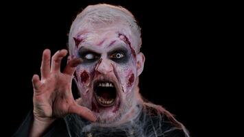 Unexpected appearance of creepy man with bloody scars face, Halloween stylish zombie make-up. Scary wounded undead guy making faces, looking at camera and screaming terribly. Sinister beast, monster video