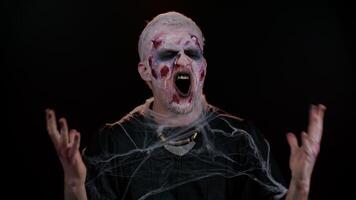 Dissatisfied frightening man with Halloween zombie bloody wounded makeup asking reason of failure, expressing disbelief irritation, feeling bored, disappointed in result, bad news. Sinister undead guy video
