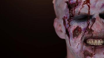 Close-up macro frightening man face with Halloween zombie blood flows and drips on face, trying to scare. Horror theme. Sinister undead guy isolated on studio black background. Serious injury wound video