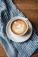 Beautiful Latte Art in a Blue Cup Placed on a Striped Napkin Indoors at a Cozy Cafe. photo