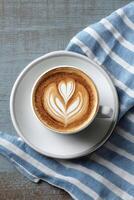Latte Art Heart Design Displayed on Coffee Cup With Striped Napkin photo