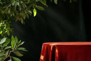Elegant Red Table Draped With Fabric Under Green Leafy Branches in a Dim Lit Room. photo