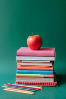 Colorful Stack of Books With Red Apple on Top Against Green Background in a Study Environment photo
