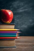 Books and Colored Pencils Arranged Neatly Beside a Red Apple on a Wooden Desk Setting photo