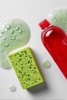 Bright Green Sponge and Red Soap Bottle With Bubbles on a White Surface During a Cleaning Session photo