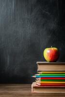 Books and Colored Pencils Arranged Neatly Beside a Red Apple on a Wooden Desk Setting. photo