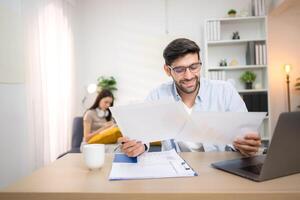 Portrait of a young freelancer smiling while working online via laptop at home with his girlfriend,150 photo