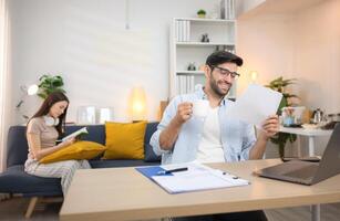 Portrait of a young freelancer smiling while working online via laptop at home with his girlfriendYoung couple are smiling while relax and working online via laptop in living room at home,136 photo