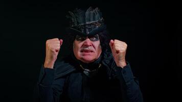 Frustrated sinister man with horrible scary Halloween witcher makeup raising hands in indignant expression, quarreling, asking reason of conflict why such stubborn. Vampire grandpa on black background video