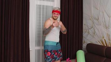 Sportsman retro guy in funny clothes waving greeting hello with hand, asking to follow, smiling and dancing at home. Portrait of fat bearded sport man hipster. Joke, comical, meme, parody, humor video