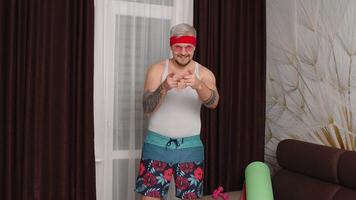 Sportsman retro guy in funny clothes dancing, pointing at camera, running at home making sport fitness cardio exercises. Dance of fat bearded man hipster of 80s. Joke, comical, meme, parody, humor video