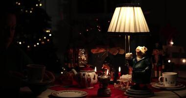 Woman enjoy a warm holiday evening tea time around Christmas table setting, then switch off the light. The whimsical pig lamp adds charm to the festive atmosphere with ambient lighting. video