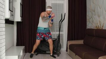 Funny Caucasian athlete sportsman guy couch making exercises with dumbbells. Stylish hipster man blogger trainer recording a sports fitness online vlog at home. Joke, comical, meme, parody, humor video