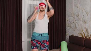 Funny Caucasian athlete sportsman guy couch making silly boxing exercises with dumbbells. Stylish hipster man blogger trainer recording sport fitness online vlog at home. Joke, comical, parody, humor video