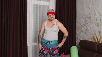 Sportsman retro guy in funny clothes showing rock and roll gesture, dancing at home making sport fitness exercises. Portrait of fat bearded man hipster of 80s dance. Joke, comical, meme, parody, humor video