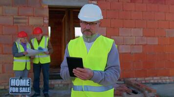 Professional builder engineer architect operate with digital tablet to control working at construction site. Foreman worker wearing hard hat, vest at building house. Business, real estate, investment video