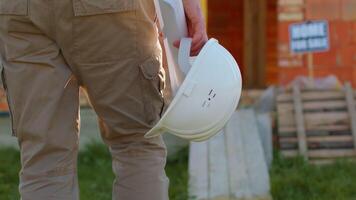 Real estate foreman designer building project architect. Professional civil engineer developer builder with helmet in hand walking to construction site. Constructor foreman. Start of working day video