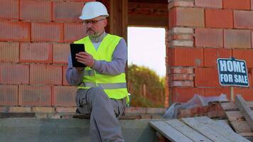 Professional builder engineer architect operate with digital tablet to control working at construction site. Foreman worker wearing hard hat, vest at building house. Business, real estate, investment video