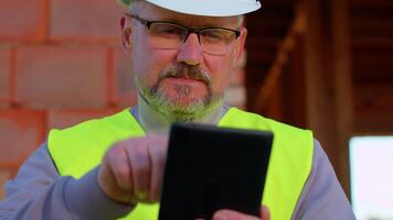 Professional builder engineer architect operate with digital tablet to control working at construction site. Foreman worker wearing hard hat, vest at building house. Business, real estate, investment video