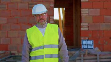 Builder engineer architect looking approvingly at camera showing thumbs up, like sign positive something good at construction site. Foreman worker at building house. Real estate, business, investment video