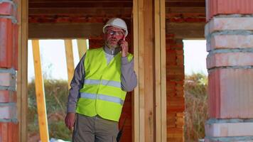 Engineer talking on phone. Architect using cell phone on construction site. Foreman phone call control process. Construction worker communications in construction industry. Building professional phone video