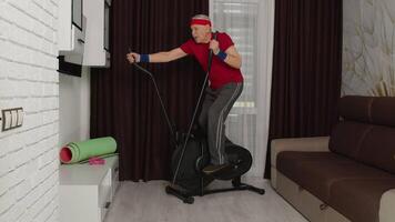 Senior man using orbitrek with vitality exercises in living room. Old pensioner grandfather training healthcare sport at home, fitness exercising workout at elderly age during coronavirus quarantine video