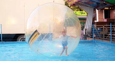 Child Playing Inside Inflatable Water Ball in Pool at Amusement Park video