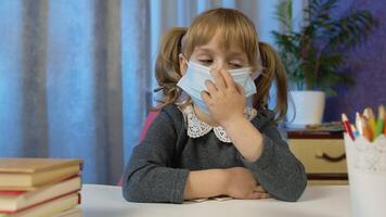 Sad child girl pupil in medical mask doing school homework at home. call by webcam on internet. Online e-learning, children pupil distance education lesson, technology for kids. Slow motion video