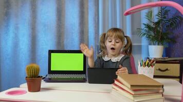 Preschool child girl distance online learning at home. Pupil kid listening audio lesson studying at table using digital tablet computer doing homework. Children remote education on covid-19 quarantine video