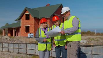 Diverse team of specialists taking near modern house. Real estate building project with senior civil engineer, architect, general worker discussing planning, development details. Purchasing, renting video