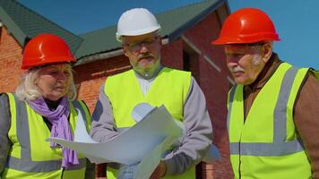 Architect with senior civil engineers discussing project work with blueprint of building house. Construction contractor working on a construction site of apartment. Discussing planning, development video