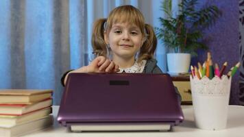 Child schoolgirl learning lessons being at home sitting at table opening laptop digital computer. Portrait of kid girl distance education. Studying on coronavirus lockdown. Slow motion. 6k downscale video