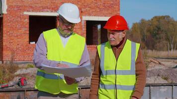 Diverse team of specialists taking near modern house. Real estate building project with senior CEO grandfather civil engineer man, architect, general worker discussing planning, development details video