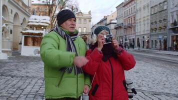 mayor antiguo Pareja turistas abuela abuelo caminando en ciudad lviv, Ucrania calles ciudad. mayor familia hombre, mujer tomando foto imágenes en cámara. Días festivos vacaciones durante coronavirus encierro video