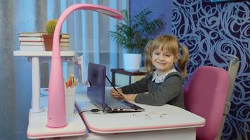 Child girl with textbook doing school homework, using laptop computer, smiling at home. Back to school, online learning distance lesson, education at home, technology for schoolgirl pupil. Slow motion video